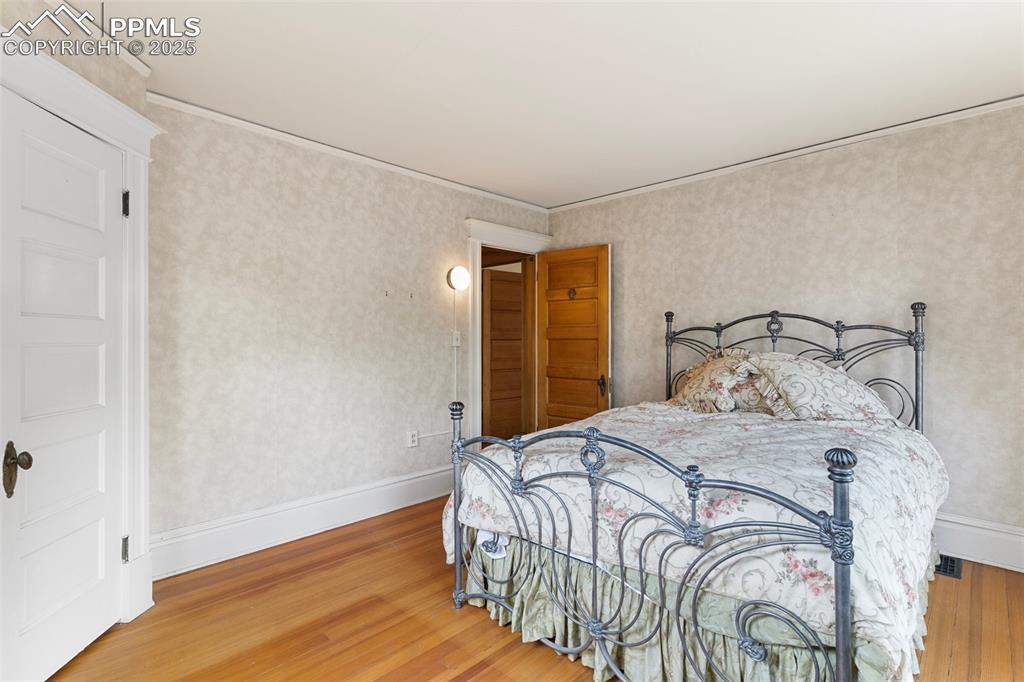 Image 27 of 50: Bedroom with wood finished floors and ornamental molding