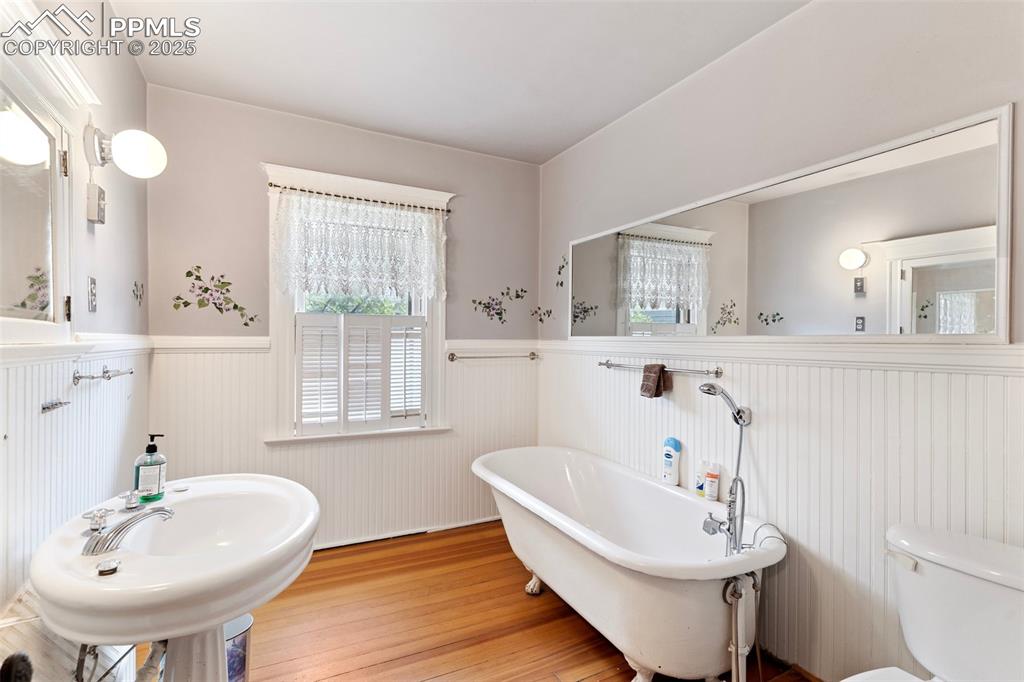 Image 31 of 50: Bathroom with wainscoting, a freestanding tub, and wood finished floors