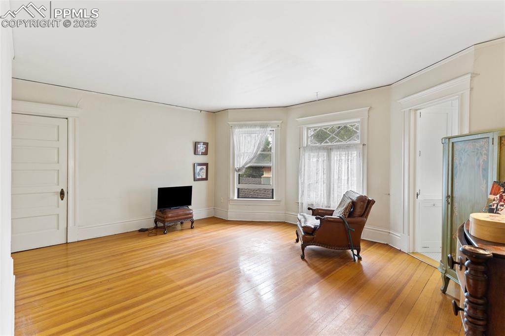 Image 32 of 50: Living area with light wood-style floors and baseboards
