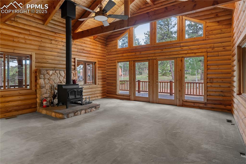 Image 10 of 45: Unfurnished living room featuring a wood stove, a wood ceiling with exposed
