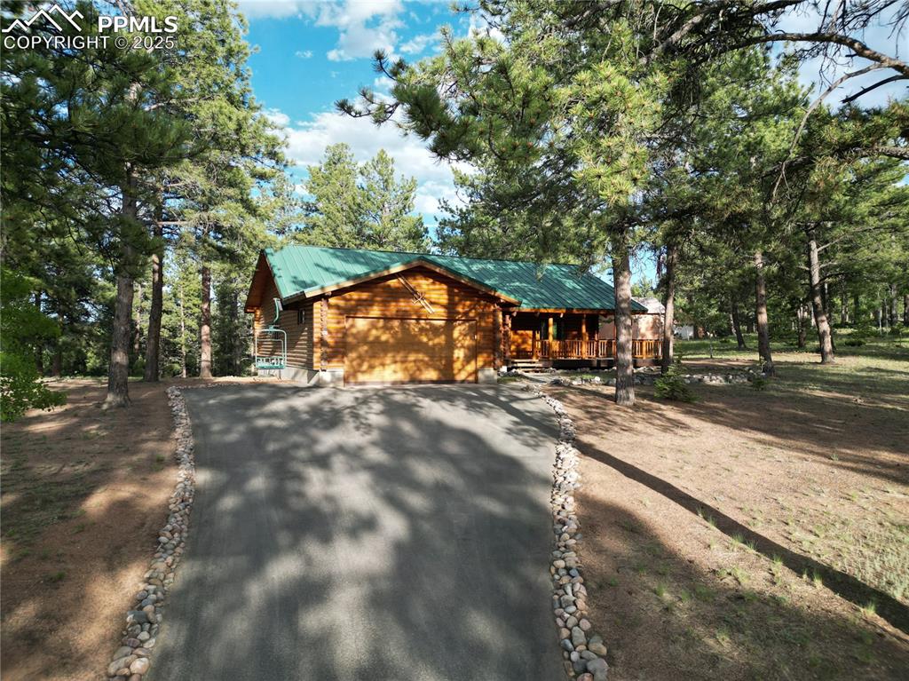 Image 43 of 45: View of front facade featuring driveway, an attached garage, and a metal ro
