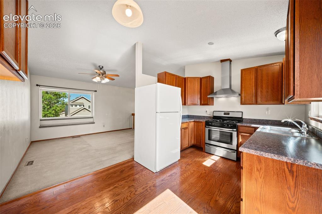 Image 12 of 40: Kitchen with wood-finish flooring, stainless steel range with overhead vent