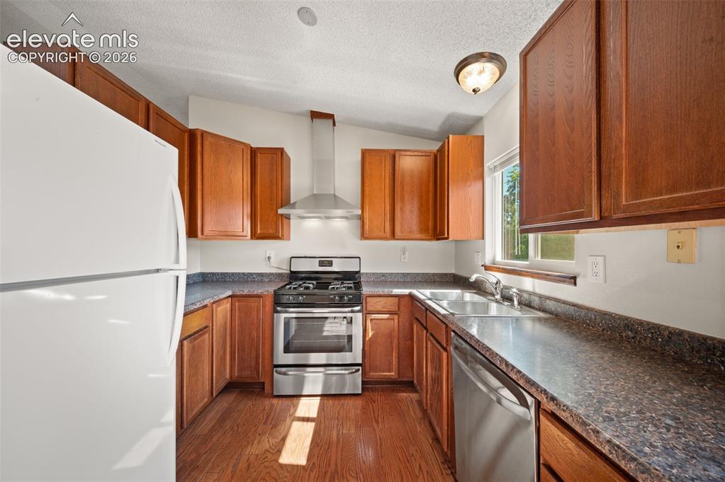 Image 13 of 40: Kitchen featuring wood-finish flooring, stainless steel appliances, wood ca