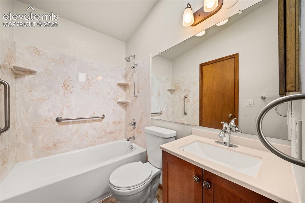 Image 16 of 40: Bathtub with shower fixture, grab bars, and integrated shelving