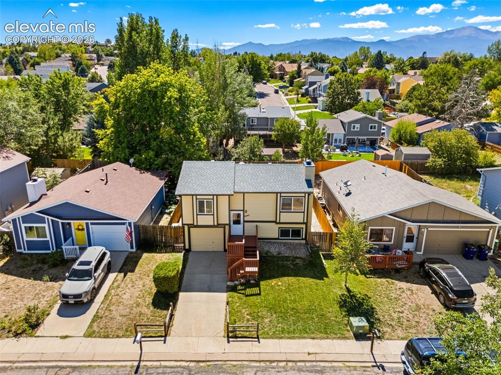 Image 2 of 40: Split-level residence featuring a pitched roof, attached garage, and a fron