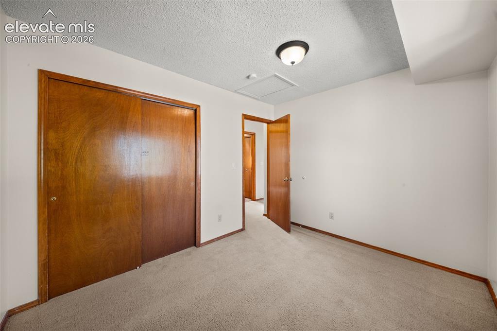 Image 21 of 40: Recessed closet with wood-finish bi-fold doors, neutral carpeting, and a fl