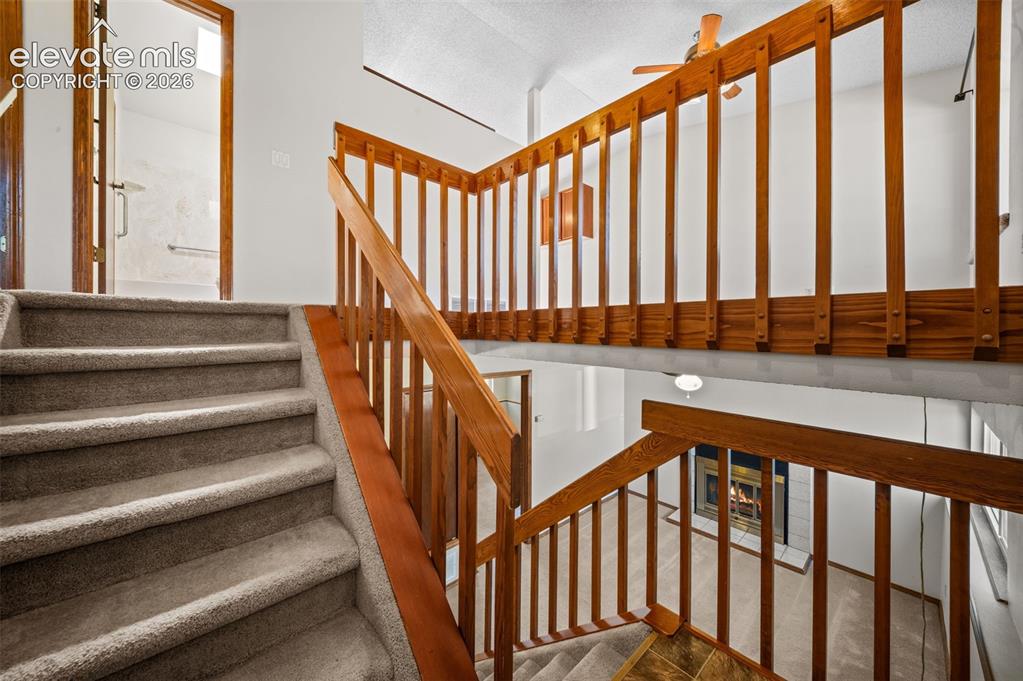 Image 23 of 40: Staircase with carpeted treads and wood handrail, open concept loft with wo