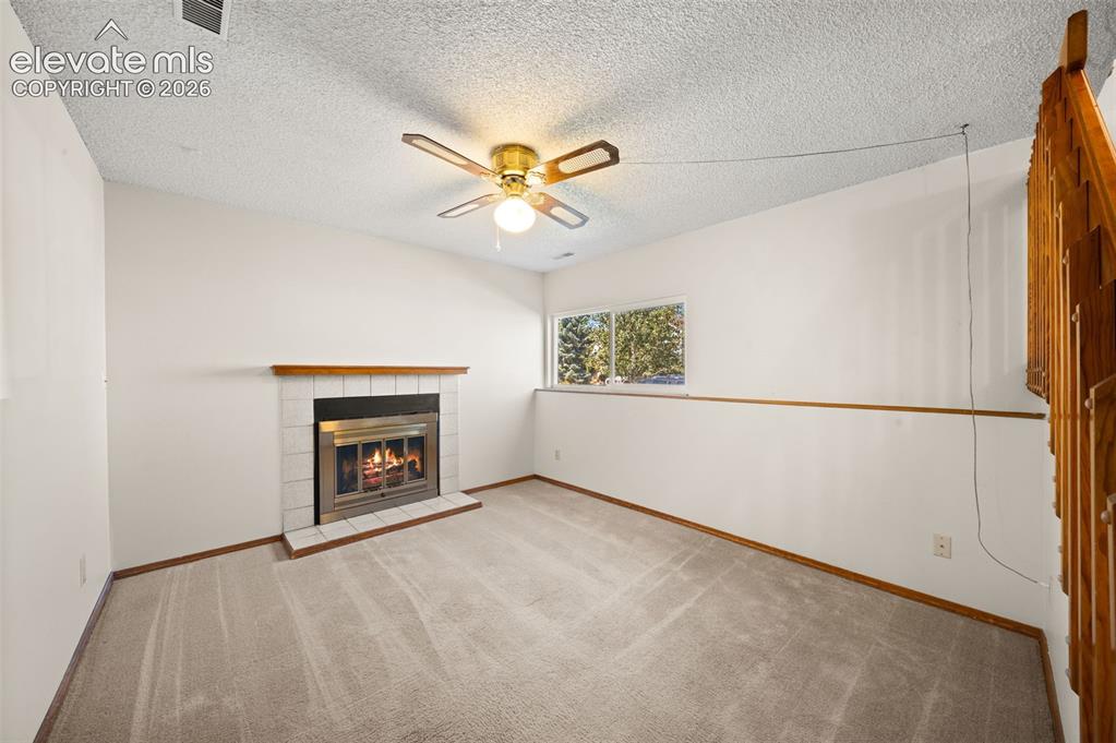 Image 24 of 40: Carpeted living space featuring a fireplace with a tile surround, a wood ma