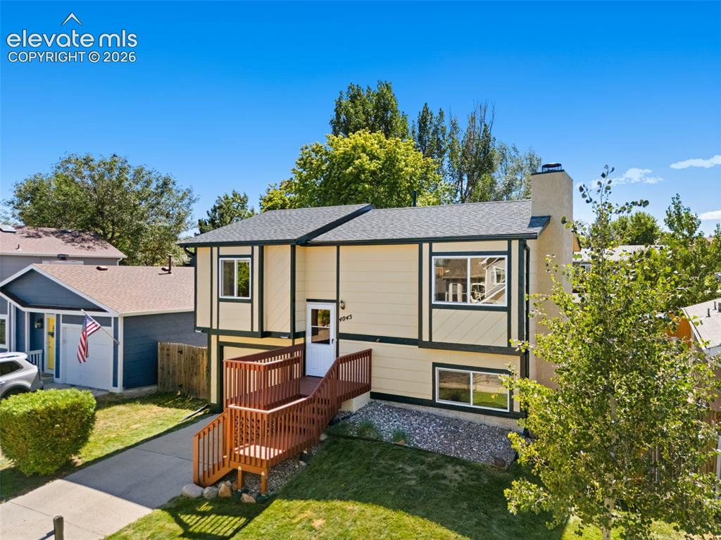 Image 3 of 40: Split-level residence featuring a light-colored exterior with contrasting t