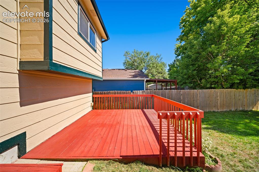 Image 30 of 40: Expansive wooden deck with a vibrant red finish and railing