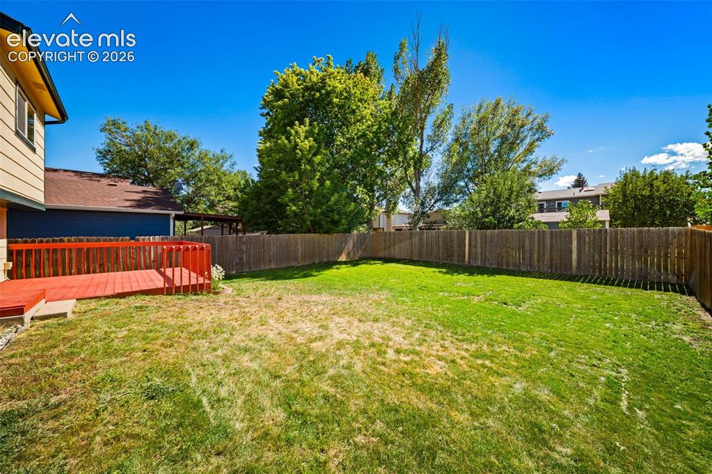 Image 33 of 40: Expansive backyard featuring a manicured lawn, full privacy fencing, and a 