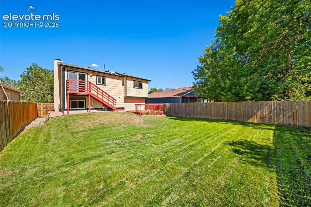 Image 34 of 40: Expansive backyard featuring a lush lawn, privacy fencing, and mature trees