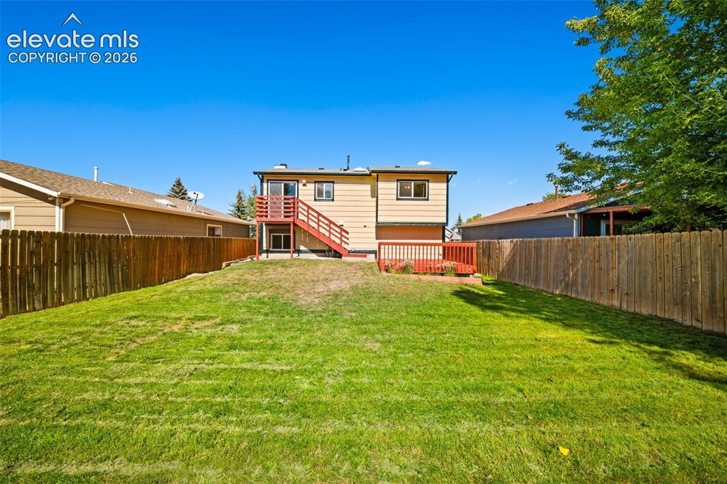 Image 35 of 40: Expansive fenced yard with a wood fence, a multi-level deck, and a sliding