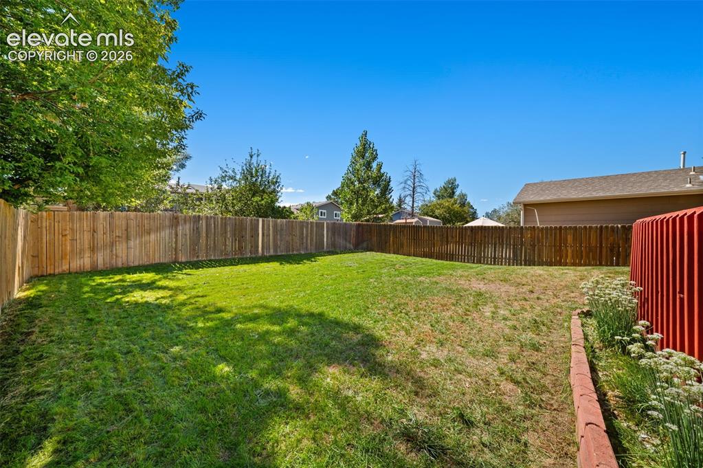Image 36 of 40: Private backyard featuring a wood privacy fence and established trees