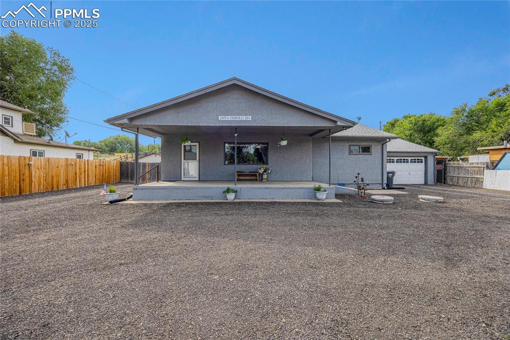 Caption: View of front of house with stucco siding, a garage, and covered porch
