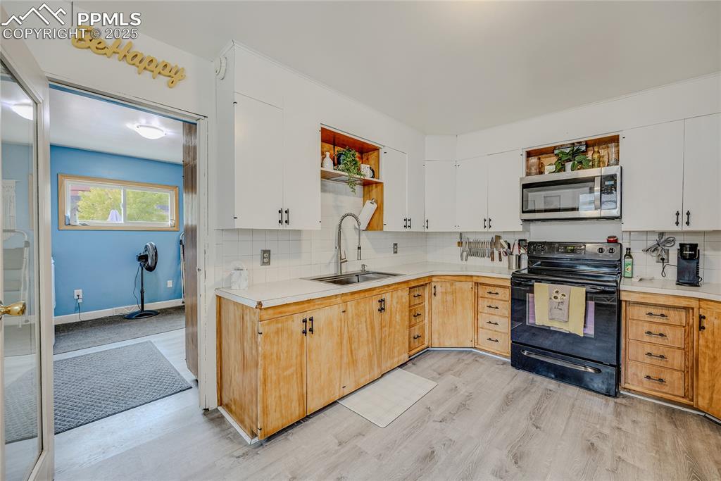Image 11 of 31: Kitchen featuring open shelves, black range, light countertops, and decorat