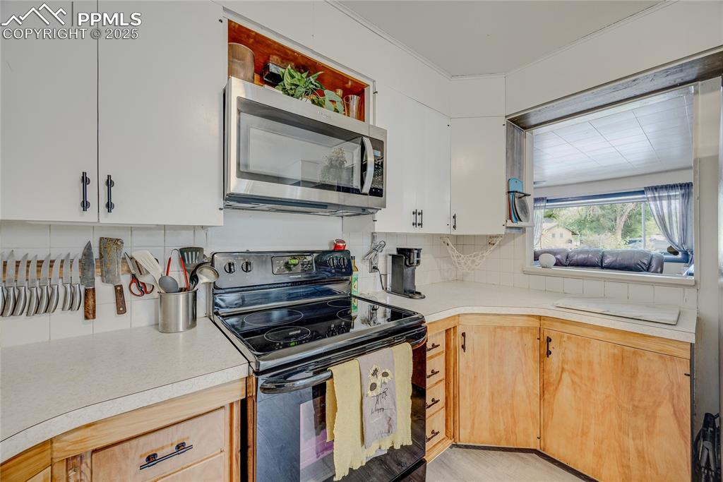 Image 14 of 31: Kitchen featuring black stove, stainless steel microwave, light countertops