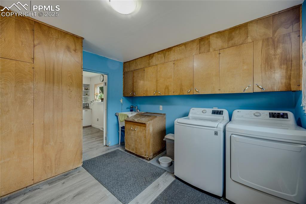 Image 15 of 31: Washroom featuring light wood finished floors, washer and clothes dryer, an