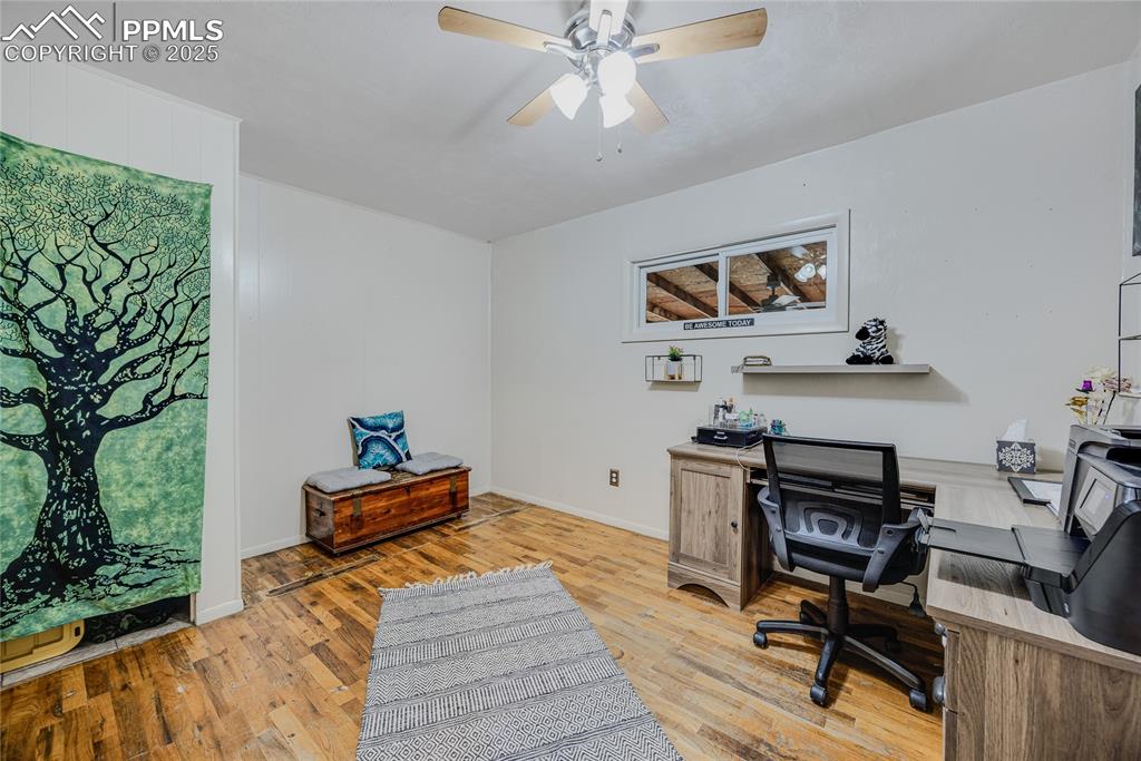 Image 16 of 31: Office area with light wood finished floors and ceiling fan