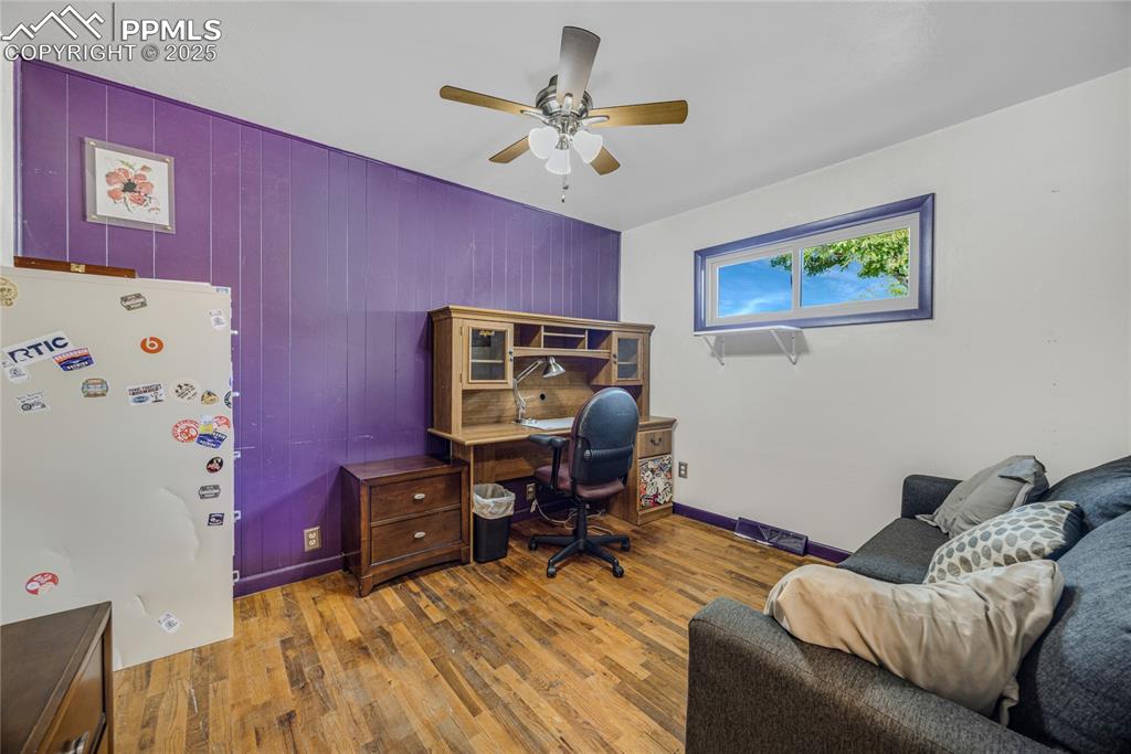 Image 19 of 31: Office with wood finished floors, wood walls, and ceiling fan