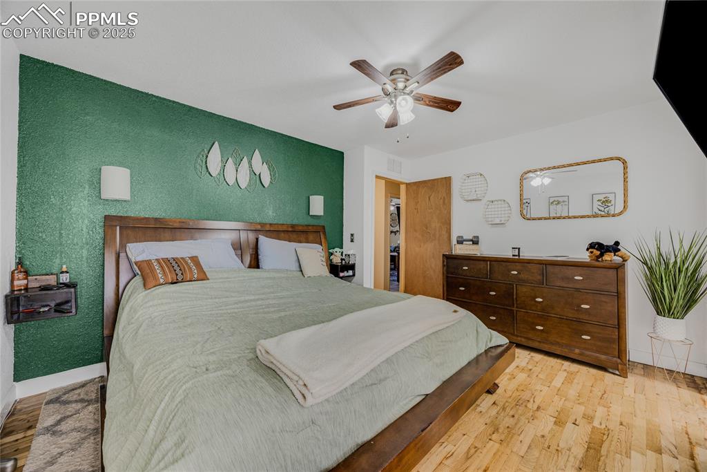 Image 22 of 31: Bedroom with wood finished floors and a ceiling fan