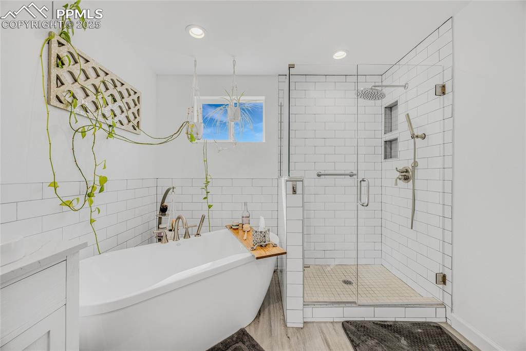 Image 24 of 31: Bathroom with tile walls, a stall shower, a freestanding tub, vanity, and r