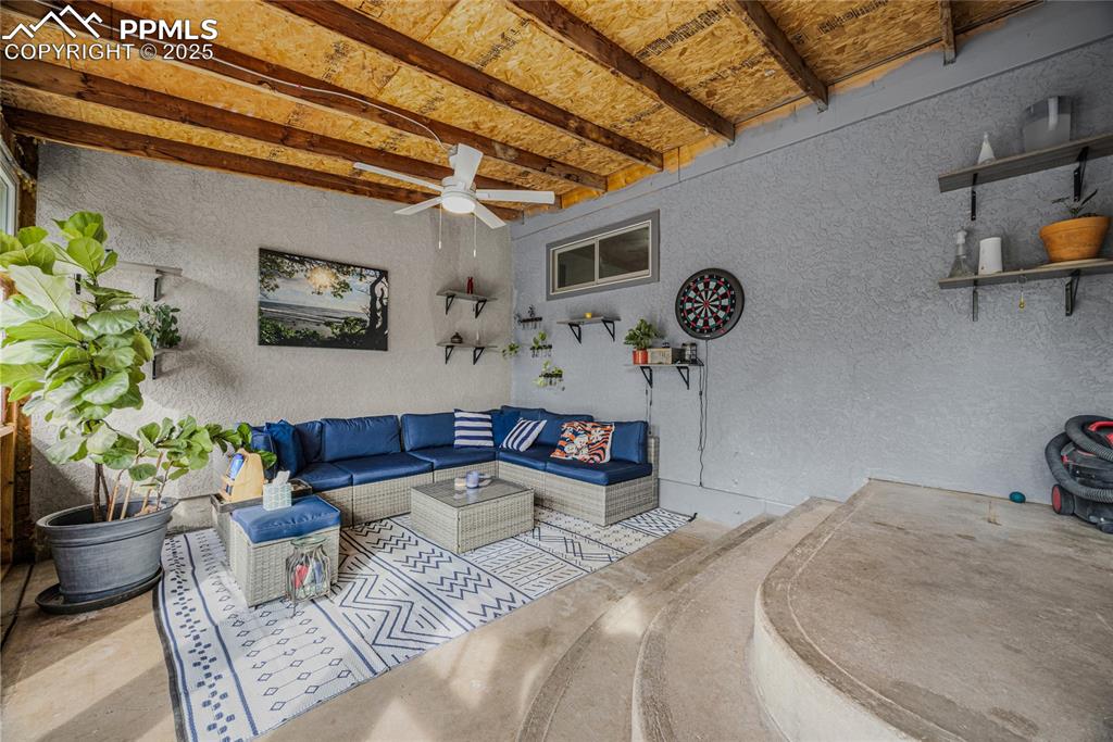 Image 26 of 31: Living room with a textured wall, a ceiling fan, concrete flooring, and bea