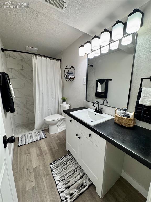 Image 18 of 27: Bathroom featuring wood-finish flooring and a white vanity with black hardw