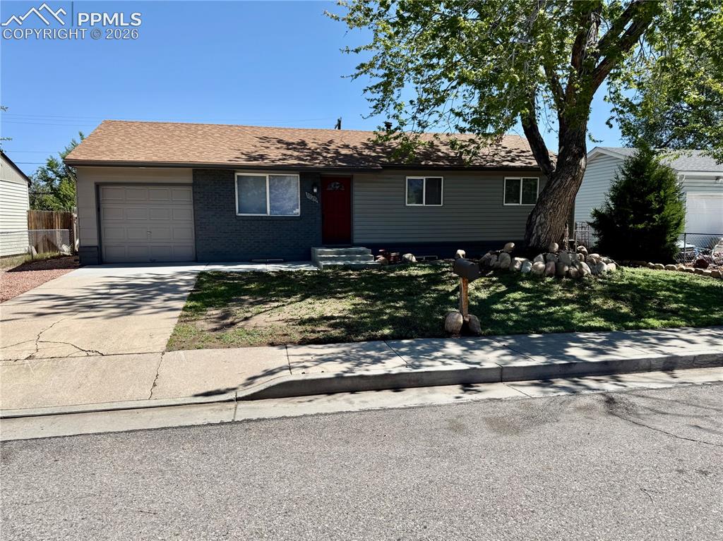 Image 2 of 27: Ranch-style residence featuring a prominent front yard with mature tree, a 
