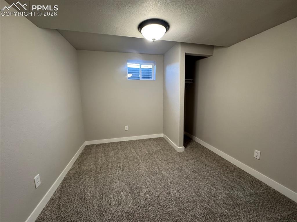 Image 20 of 27: Compact room featuring neutral painted walls, textured carpet, white basebo