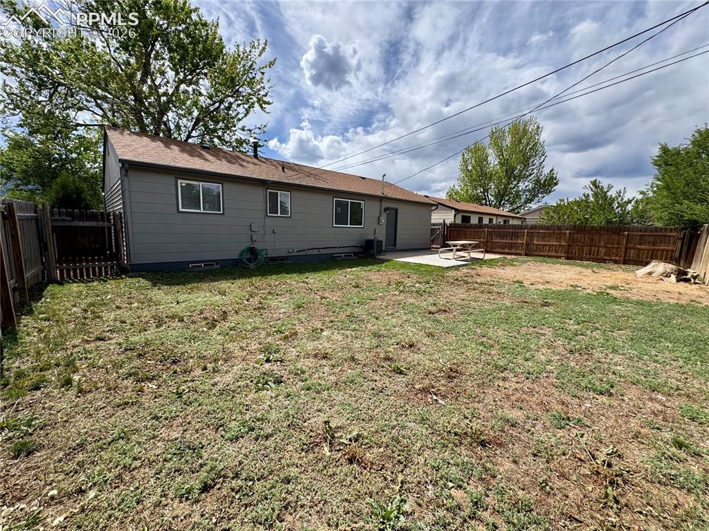 Image 21 of 27: Expansive rear yard featuring a concrete patio, wood privacy fencing, and m