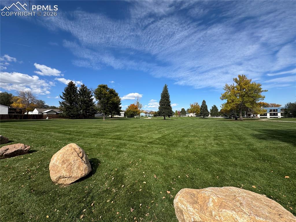 Image 24 of 27: Expansive green lawn featuring mature trees and scattered boulders