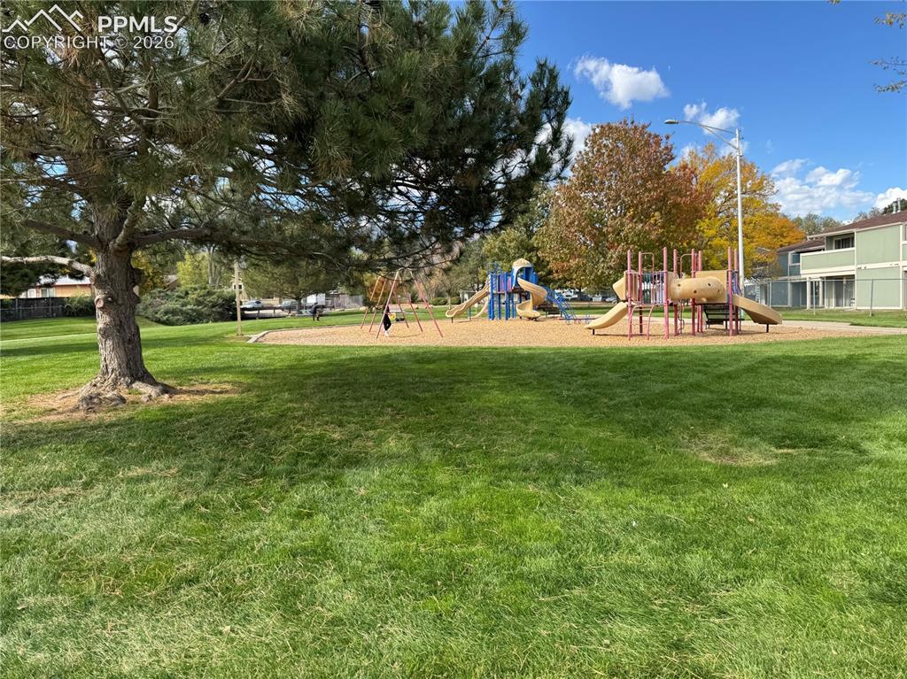 Image 25 of 27: Community playground featuring multiple slides, swings, and climbing struct