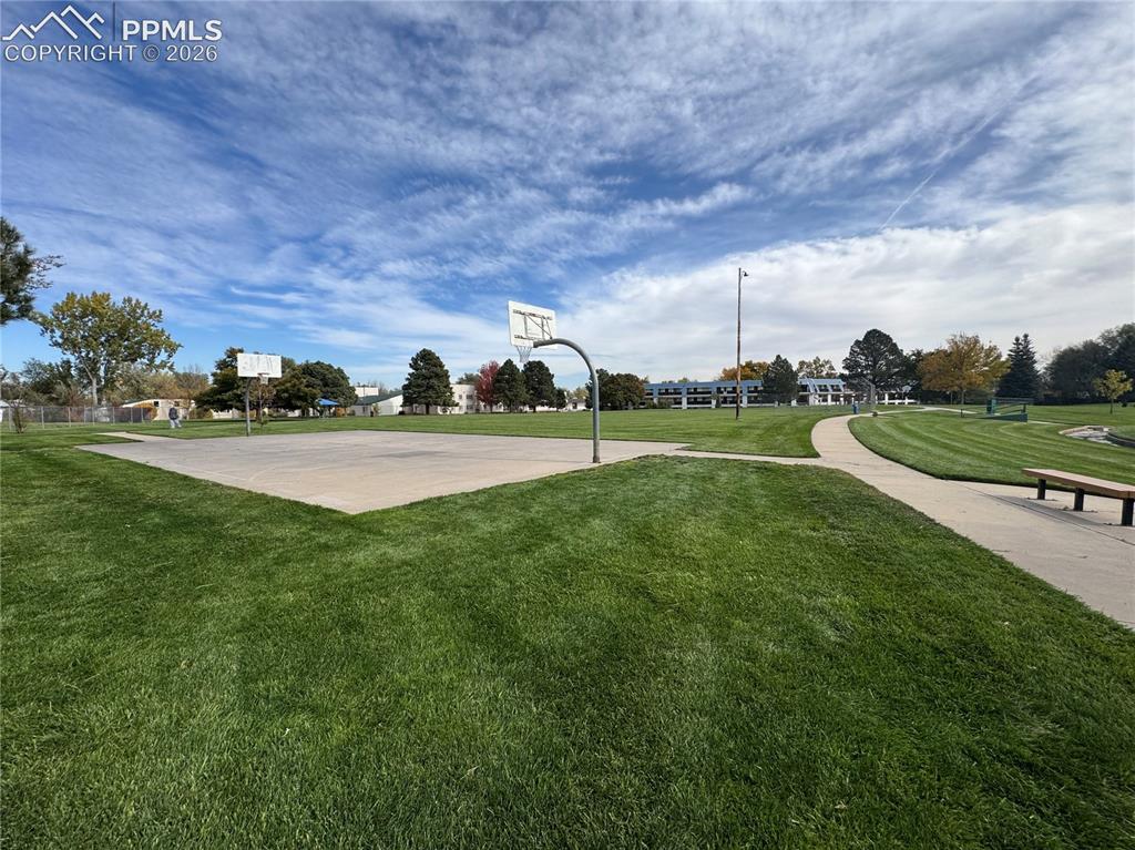 Image 27 of 27: Spacious park setting featuring a concrete basketball court with two hoops,