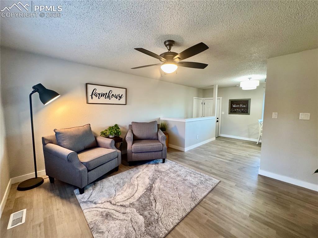 Image 3 of 27: Open-concept living space featuring wood-finish flooring, a ceiling fan wit