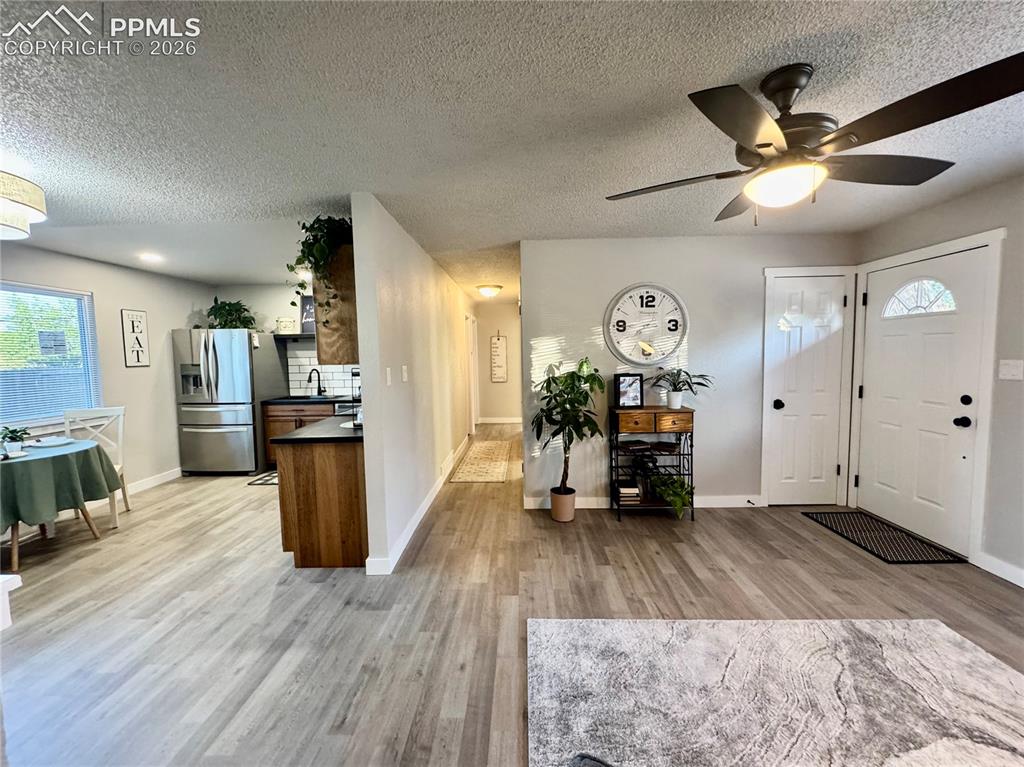 Image 5 of 27: Open-concept living space featuring wood-finish flooring, a modern black ce