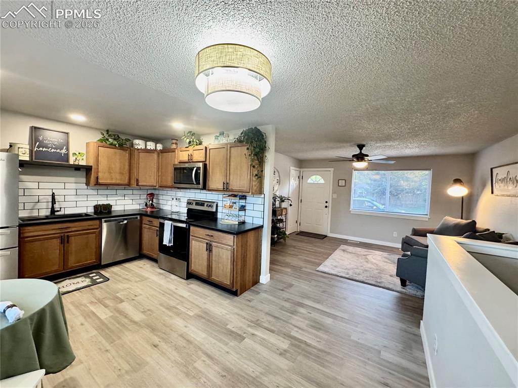 Image 6 of 27: Open-concept living area featuring wood-finish flooring throughout, a kitch