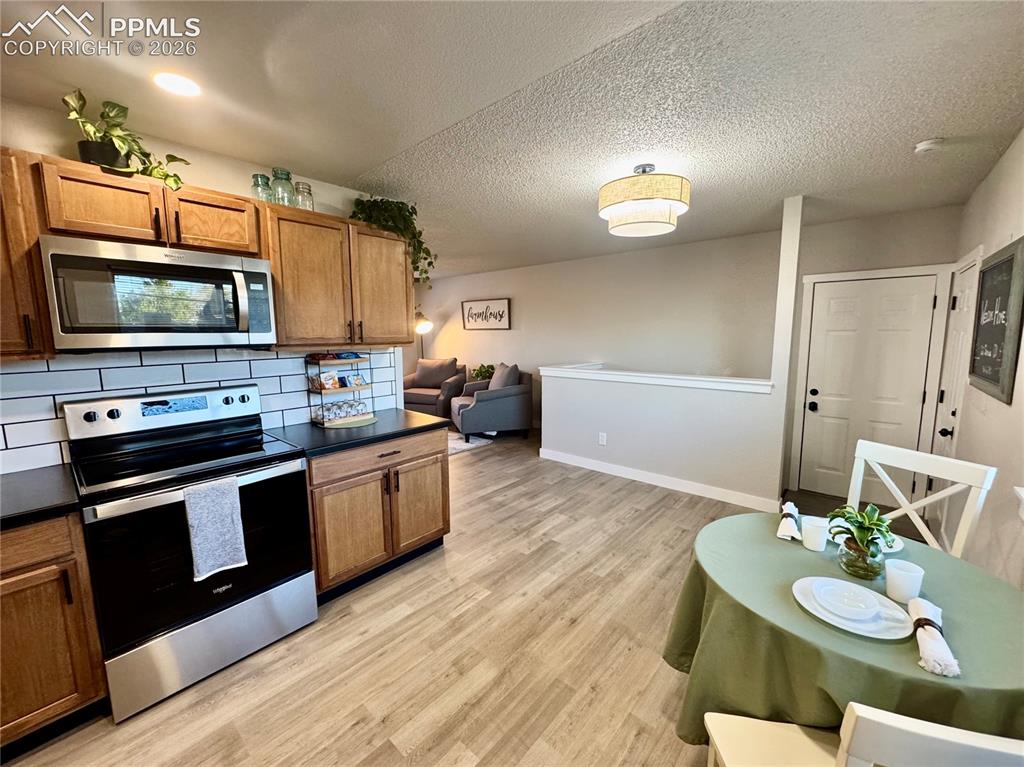 Image 8 of 27: Kitchen featuring stainless steel appliances, wood-finish cabinetry, subway