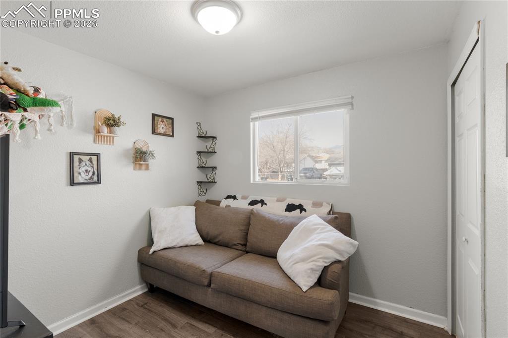 Image 10 of 32: Living area with dark wood-style flooring and a textured wall