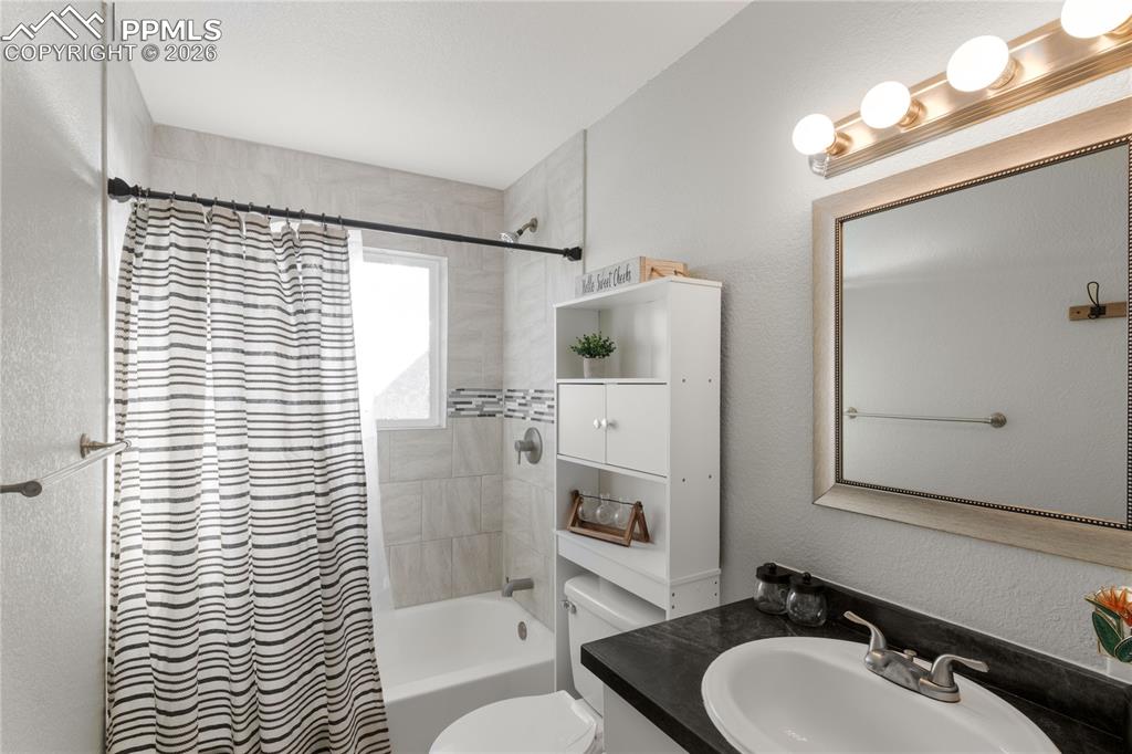 Image 17 of 32: Full bath with a textured wall, shower / bath combo with shower curtain, an