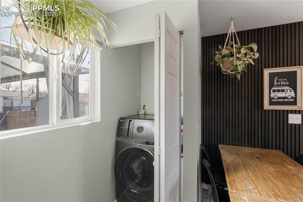 Image 27 of 32: Laundry area with a textured wall and washer / dryer