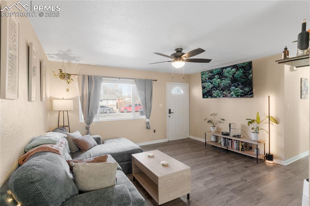 Image 8 of 32: Living area with wood finished floors and ceiling fan
