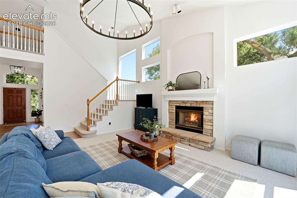 Image 12 of 50: Soaring ceilings with an oversized chandelier, stone-surround fireplace, la