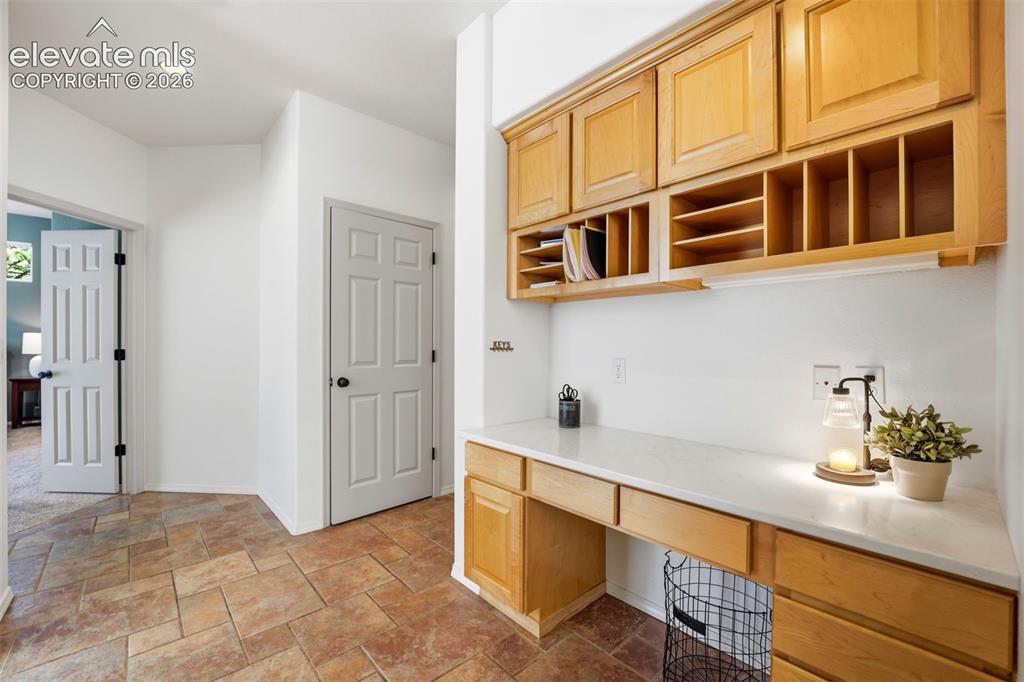 Image 15 of 50: Built-in desk area with light wood-finish cabinetry, integrated shelving, w