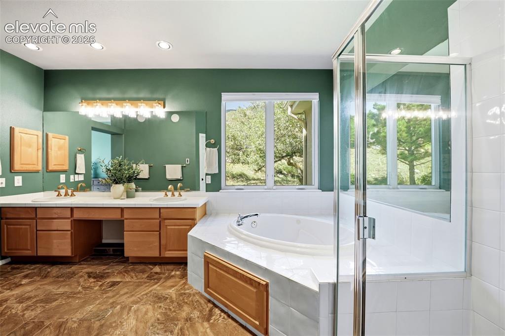 Image 18 of 50: Dual vanity with extensive countertop space, wood-finish cabinetry, and an
