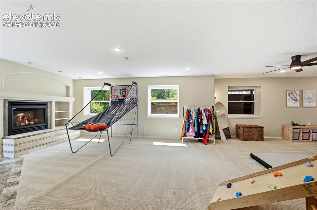 Image 25 of 50: Spacious room featuring a fireplace with a tile hearth, built-in shelving, 