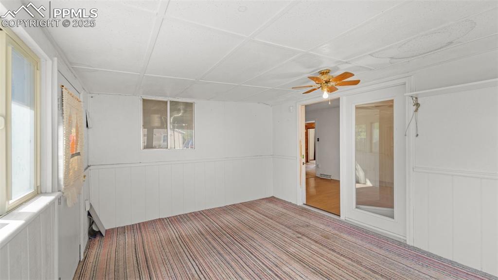 Image 20 of 33: Carpeted empty room with a drop ceiling, a wainscoted wall, and ceiling fan