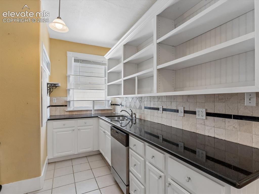 Image 13 of 35: Kitchen featuring open shelving, white cabinetry, dark countertops, a stain
