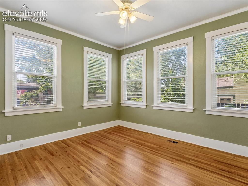 Image 16 of 35: Spacious room featuring hardwood flooring, multiple windows with white blin