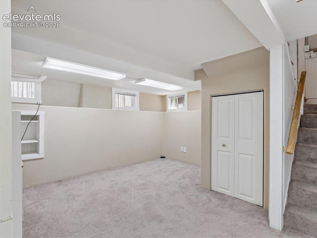 Image 18 of 35: Carpeted room featuring multiple egress windows, built-in shelving, bi-fold